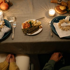 Elegant Thanksgiving dinner setting with candlelights, plates, and festive decor.