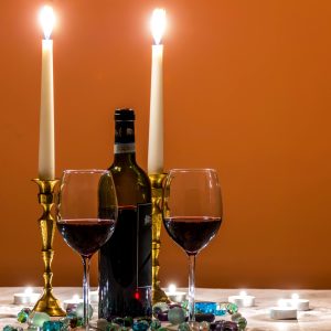 Cozy candlelit dinner setting with red wine and elegant glassware for a luxurious dining experience.